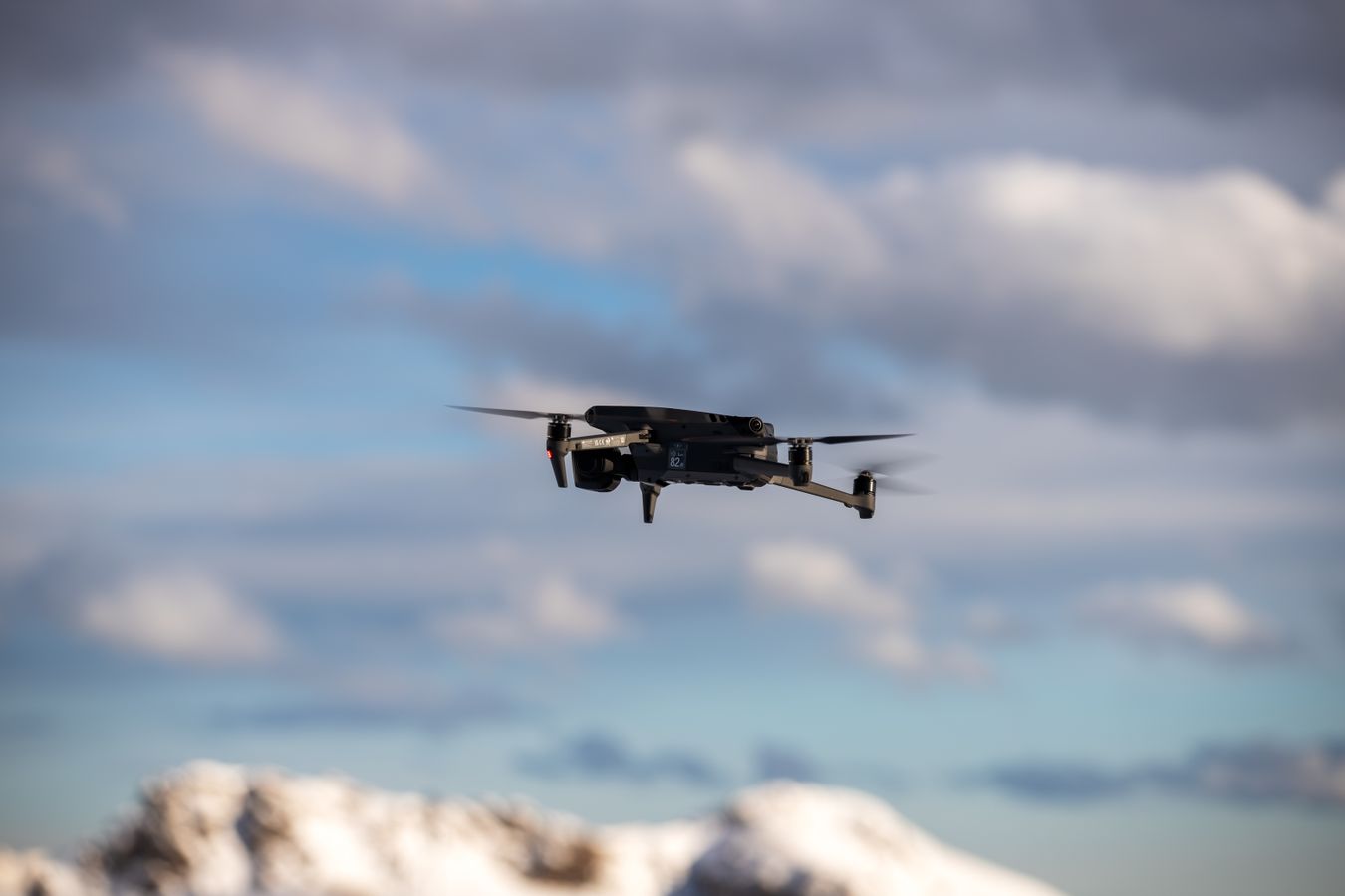 Drone en vol au-dessus d'un paysage de montagnes enneigees, teleplotage a distance