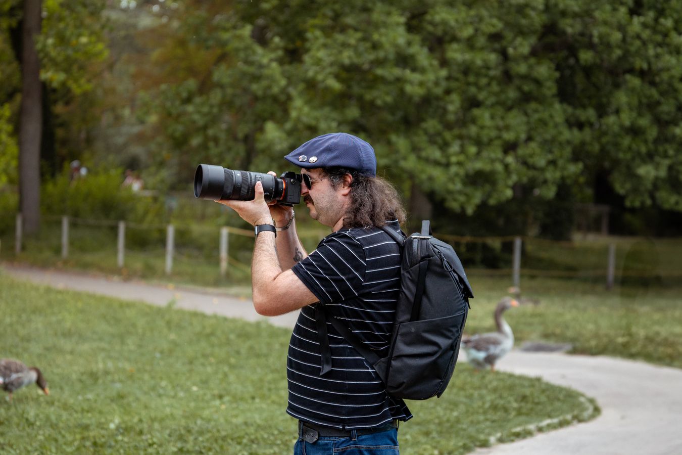 Photographe muni d'un téléobjectif prenant des clichés en extérieur dans un parc