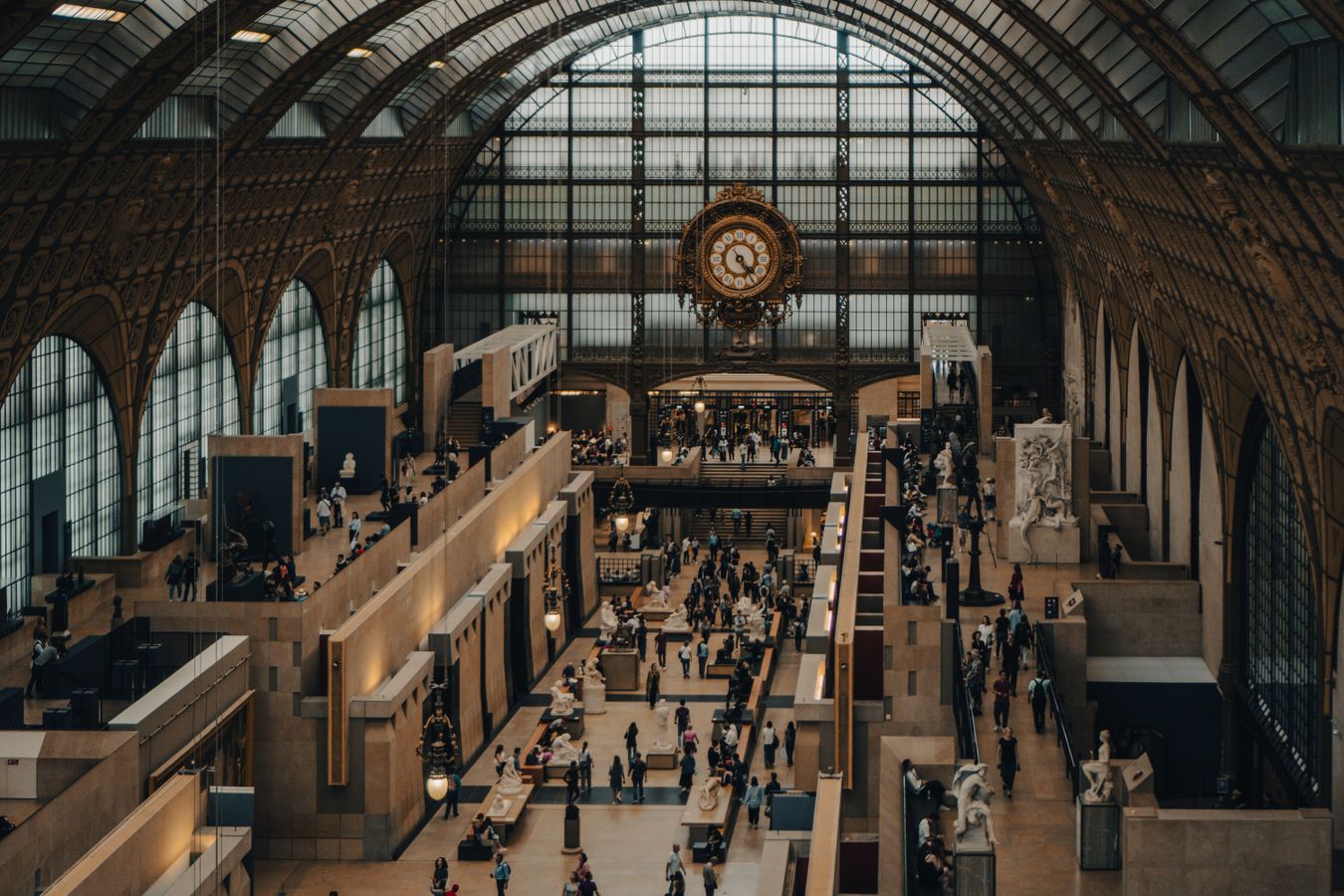 Visiteurs circulant dans une vaste salle d'exposition sous verriere, ambiance musee patrimonial