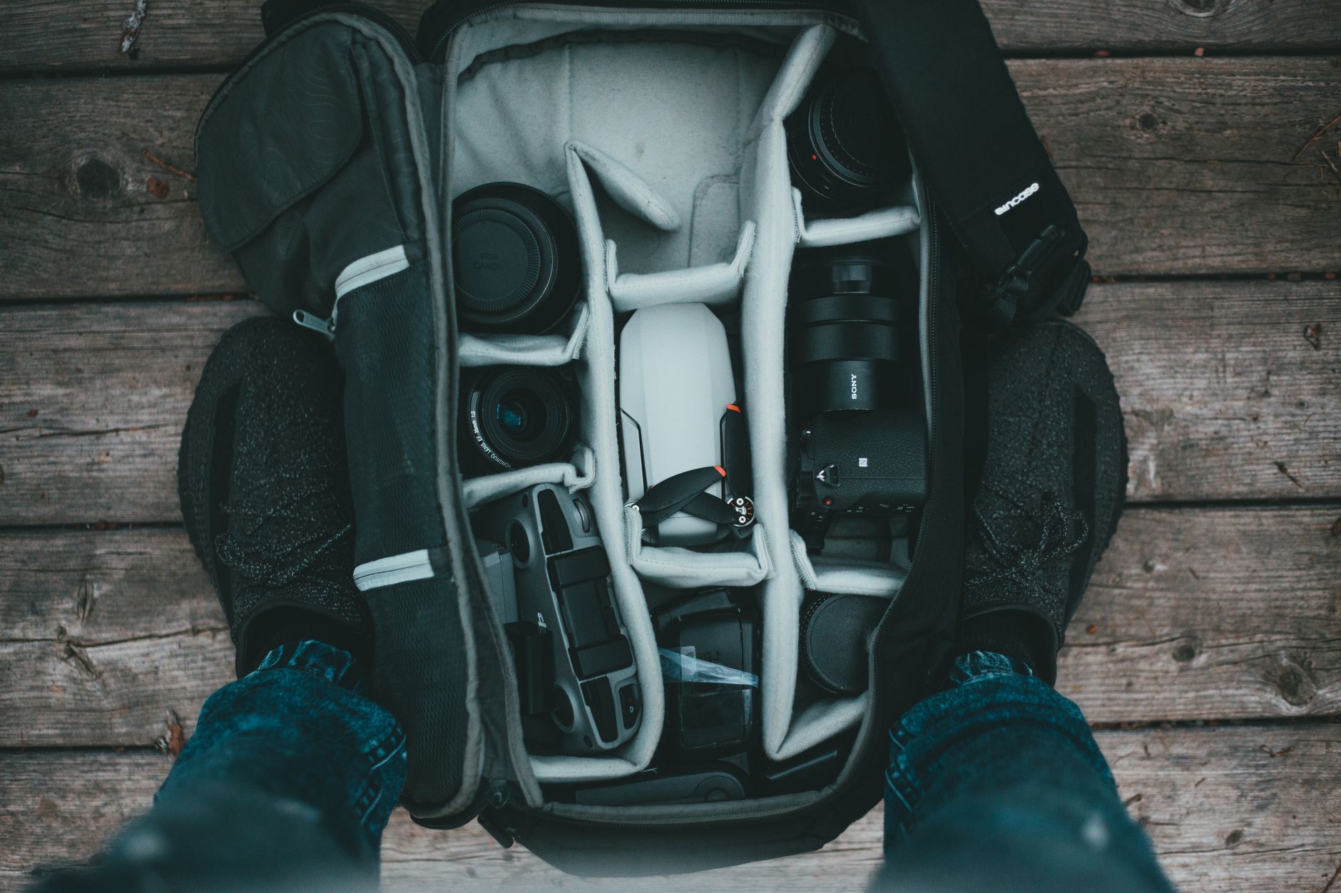 sac photo ouvert vu de dessus, rangé avec un boîtier, plusieurs objectifs et un drone compact