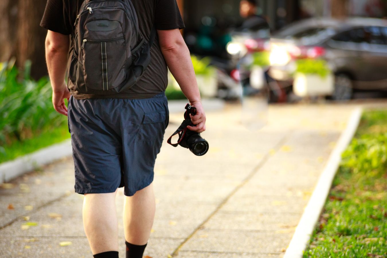 Photographe solo marchant dans la rue avec sac à dos et appareil photo à la main