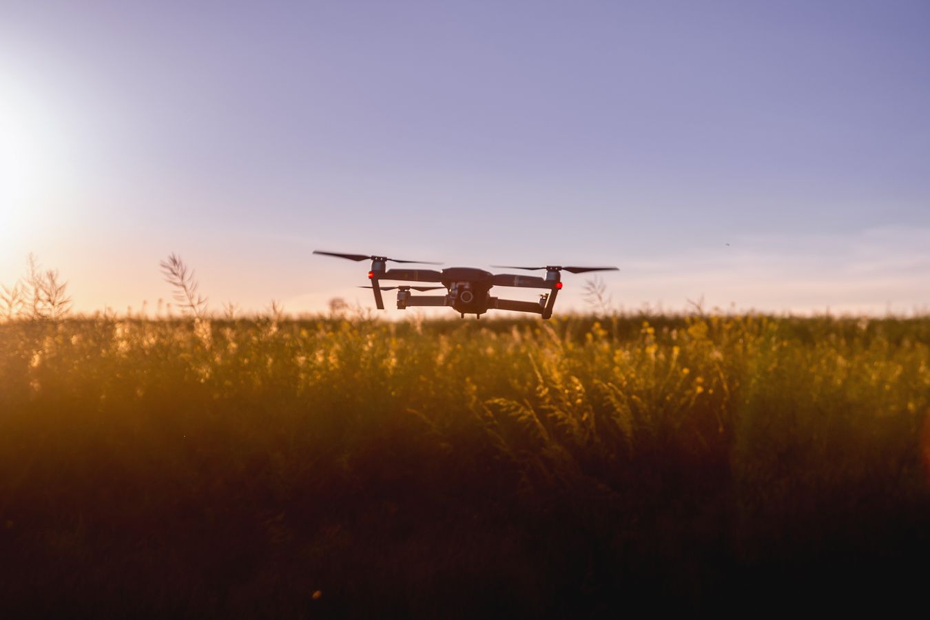 Drone en vol stationnaire au-dessus d'un champ au coucher du soleil