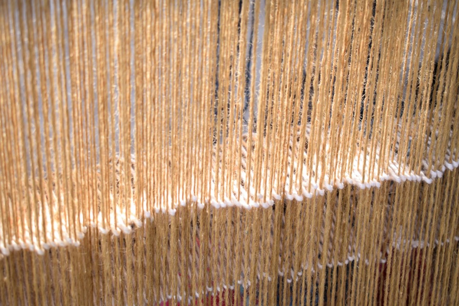 mains d'une tisseuse manipulant du fil de coton sur un métier à tisser traditionnel